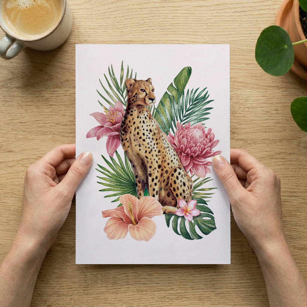 Person holding a print with a cheetah and floral design on a wooden table with a cup of coffee and plant.