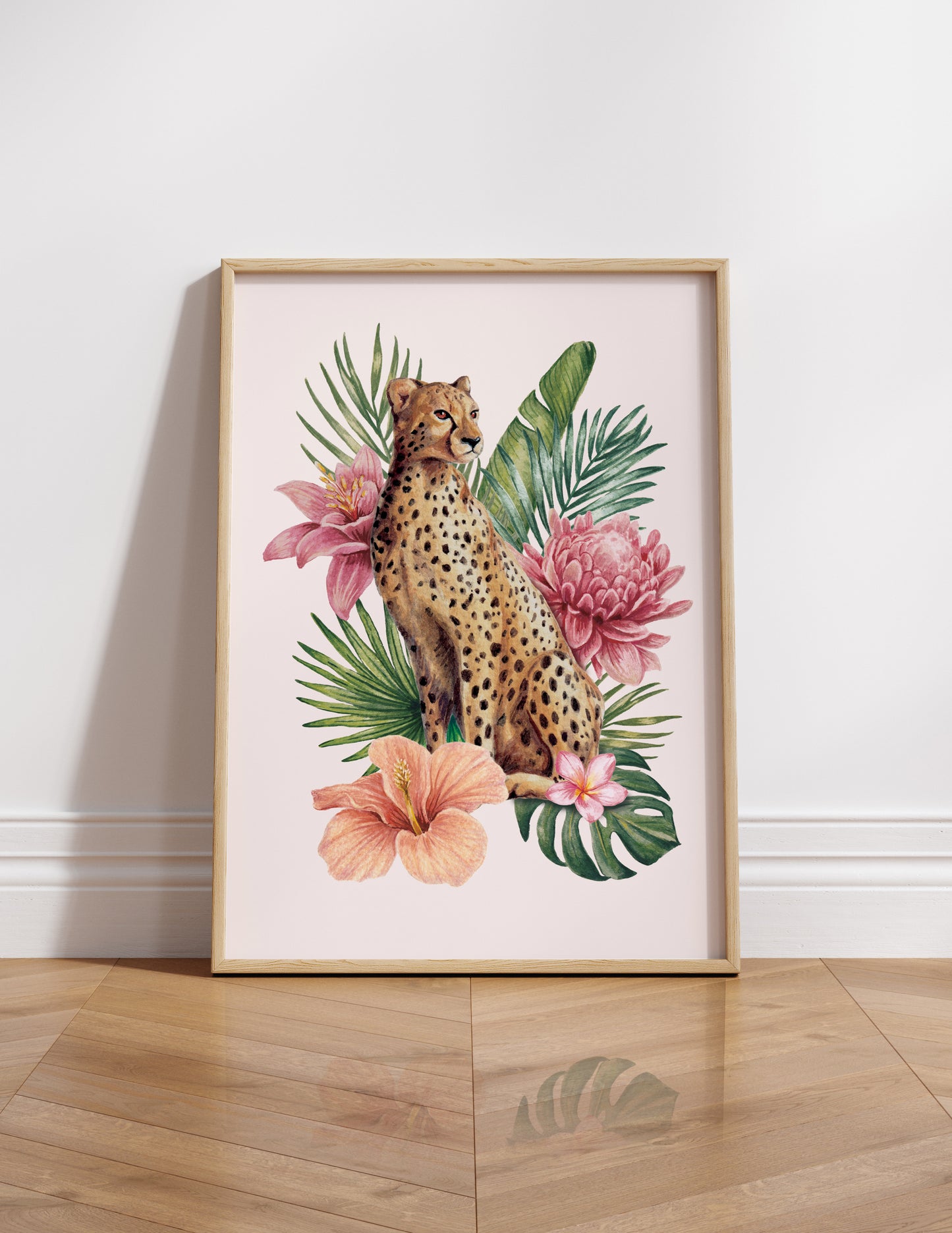 Framed artwork of a cheetah among tropical flowers and leaves on a white wall.