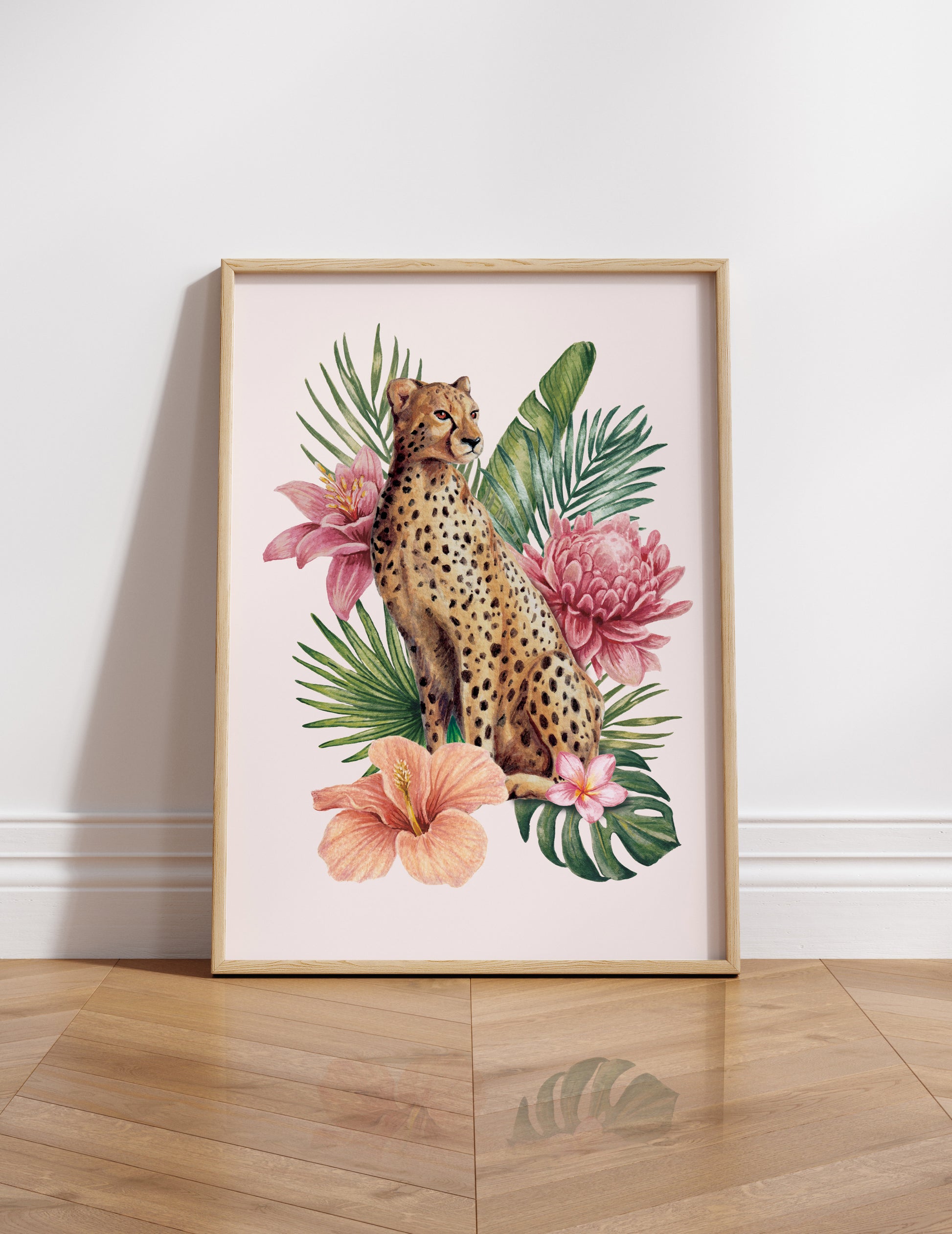Framed artwork of a cheetah among tropical flowers and leaves on a white wall.