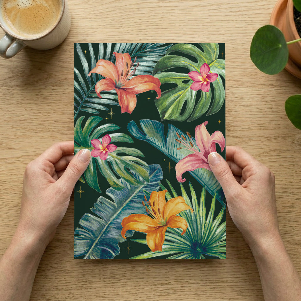 Person holding an art print with tropical floral design on a wooden table with a cup of coffee.