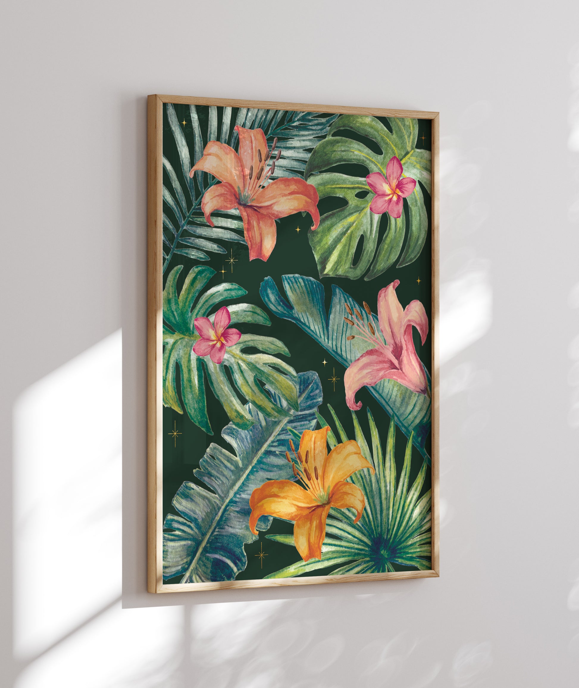Framed artwork of tropical leaves and flowers on a white wall